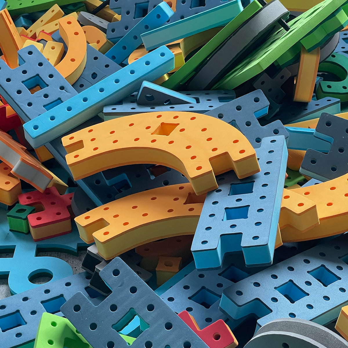Close-up texture view of durable, waterproof BAKOBA foam building blocks in bright blue, orange, and green