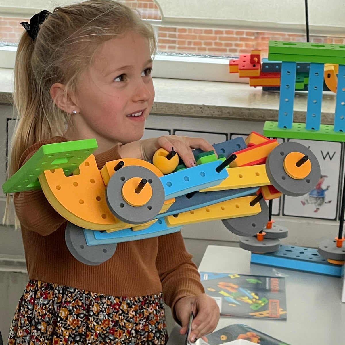 Smiling girl showcasing her custom vehicle build using BAKOBA educational construction toys