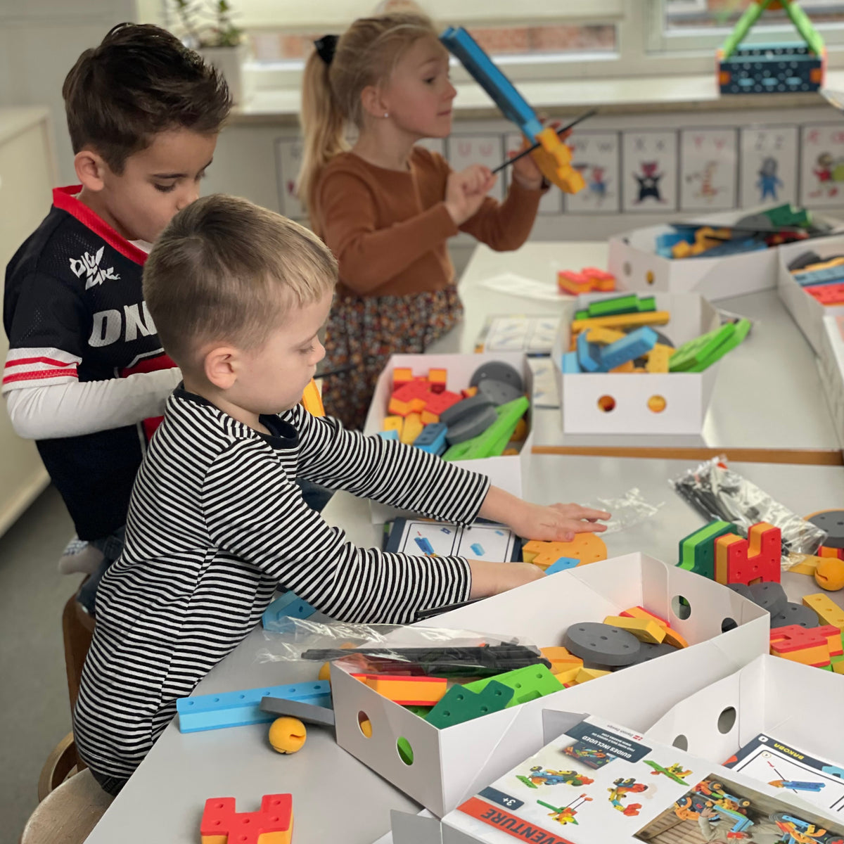 Children working together at a classroom table sorting and building with BAKOBA STEM toy sets